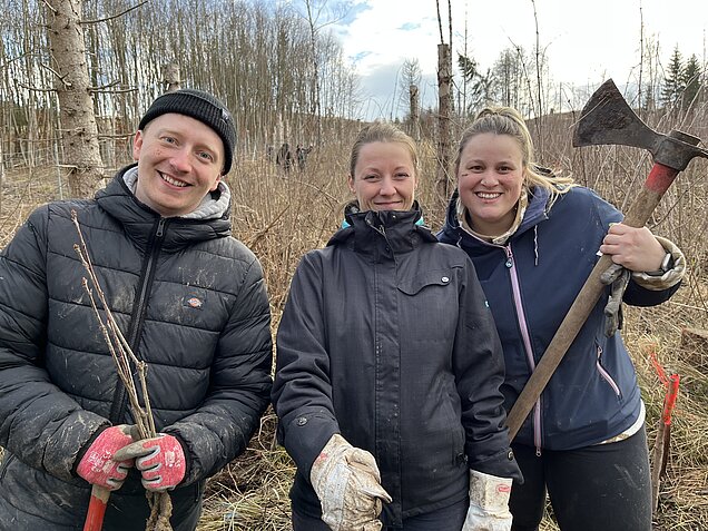 Mitarbeiter des UKA bei einer Waldfreunde Pflanzaktion ausgerüstet mit Handschuhen und Hacke auf der Fläche.