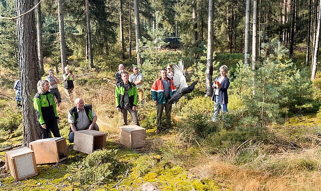 Gruppe von Personen im Wald beobachtet ein in die Luft fliegendes / startendes Auerhuhn