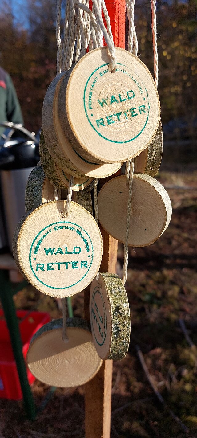 Eine Medaille aus einer Holzscheibe mit dem Aufdruck Wald-Retter-Woche